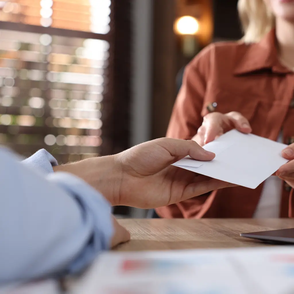man handing envelope to woman